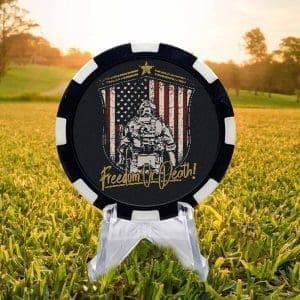 Black and white golf ball marker poker chip featuring a an American Soldier with back towards the viewer facing an American flag backdrop with "freedom or death" along the bottom; all against a black background.