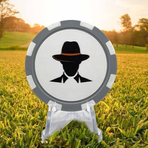 Poker chip style golf ball marker featuring a gray and white border and a silhouette of a man wearing a fedora style hat with an orange band.